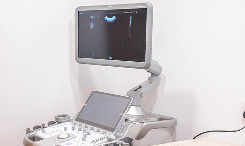 Ultrasound machine with monitor and control panel in a clinic.