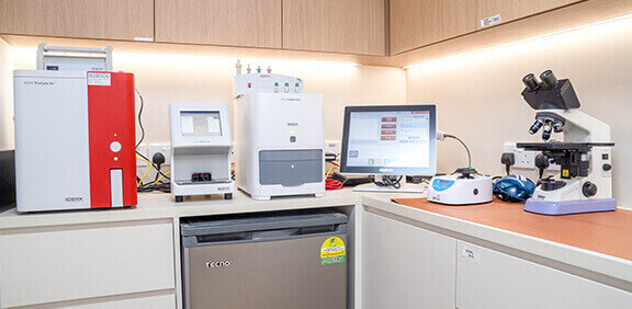 Modern laboratory setup with diagnostic machines, computer monitor, and microscope on a clean workstation.